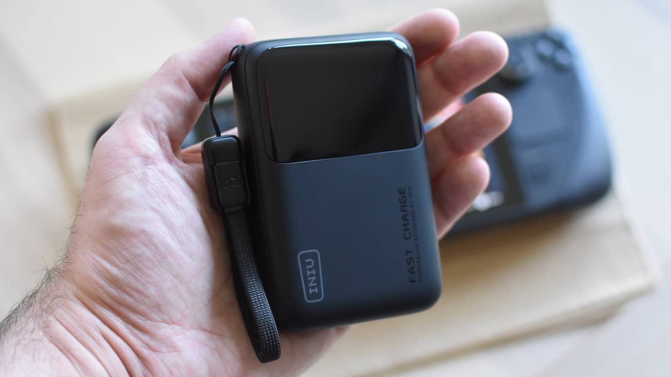 The Iniu 65W 20000mAh Portable Charger being held in a hand.